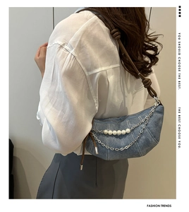 Detail of light blue denim crossbody dumpling bag with pearl chain and knot shoulder strap