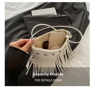Vue intérieure du sac blanc à franges et rivets montrant l'espace pour maquillage et mobile