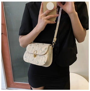 Détail du sac bandoulière en paille avec broderie florale et boucle fer à cheval dorée