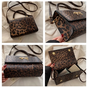 Detail of leopard print handbag featuring a gold bow buckle and adjustable strap