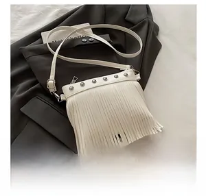 Détails d'un sac bandoulière blanc avec franges bohèmes et clous métalliques argentés