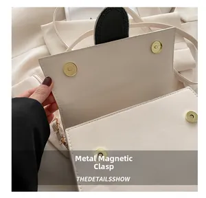 Detail des goldenen Magnetverschlusses an der cremefarbenen Leder-Schultertasche