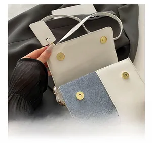 Detail of high-quality golden magnetic buckle on white and denim patchwork crossbody bag