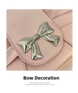 Détail d'un sac à main en cuir rose orné d'un nœud décoratif en métal argenté poli
