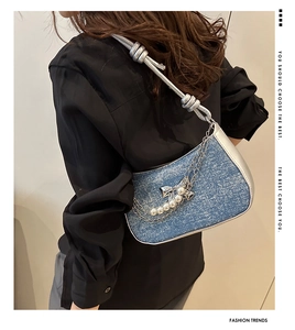 Detail of blue denim shoulder bag with silver leather trim and pearl star chain strap