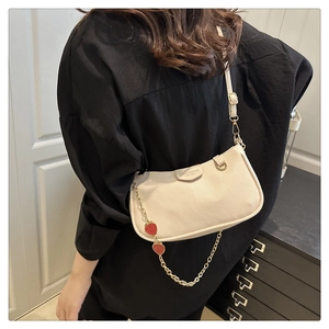 Detail of cream lychee leather shoulder bag with gold chain and strawberry charms