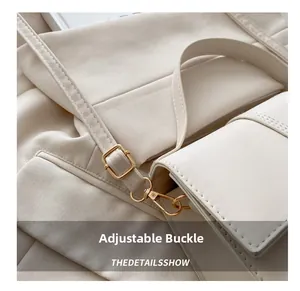 Detailaufnahme der goldenen verstellbaren Schnalle und des Lederriemens einer weißen Handtasche