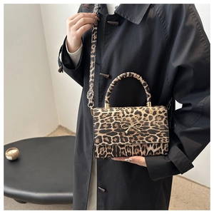 Close-up of leopard print crossbody bag with a gold metal bow and adjustable strap