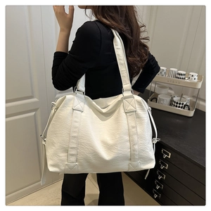 Detail of a white large tote bag with lychee grain texture and side adjustment straps