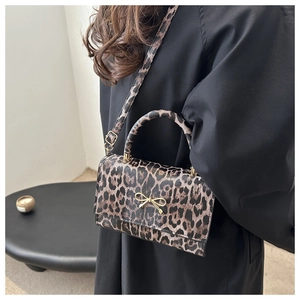 Detail of leopard print handbag featuring a gold bow clasp and adjustable shoulder strap