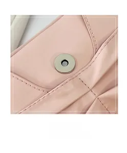 Gros plan sur le fermoir magnétique et les coutures de ce sac à main plissé rose