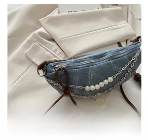Dettaglio della cerniera argentata e catena di perle sulla borsa in denim blu