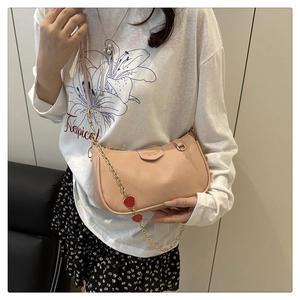 Detailed shot of pink lychee leather bag with gold chain and red strawberry charms