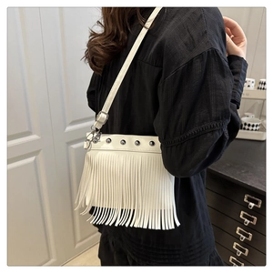 Detail of white leather bucket bag featuring silver rivets and long fringe tassels
