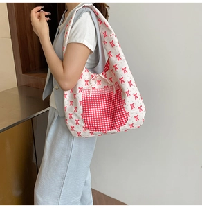 Detail of floral canvas tote bag featuring a red checkered pocket and bow patterns