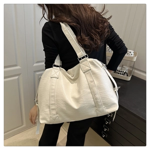 Close-up of white lychee texture leather tote bag worn on shoulder by a model