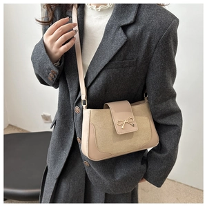 Detail of beige PU leather crossbody bag with a golden metal bow fastener and slim strap