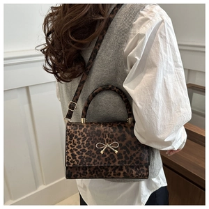 Detail of leopard print crossbody bag with gold bow ornament and adjustable strap