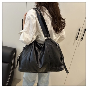 Black pebbled faux leather tote bag being worn by a model to show large capacity and size