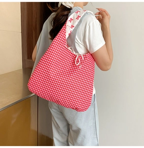 Detail view of red gingham tote bag featuring ribbon bow tie and floral inner lining