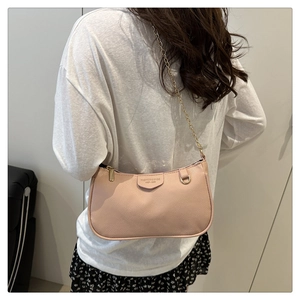 Detail of pink lychee leather handbag featuring a gold chain strap and half-moon design