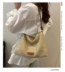 Detail of hand-woven straw tote with leather fashion tag and thin brown strap