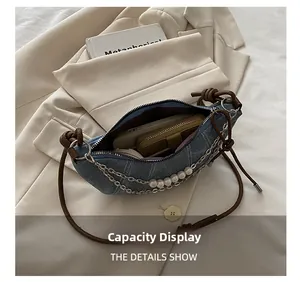 Dettaglio che mostra la grande capacità della borsa denim a mezzaluna con perle