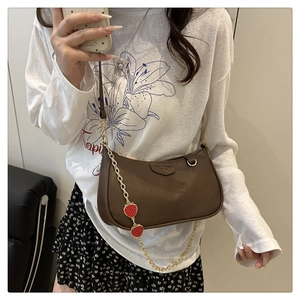 Detailed view of coffee brown lychee leather bag with cute strawberry charms and gold chain