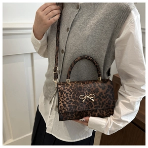 Detailed side view of leopard print crossbody bag with a decorative gold bow buckle