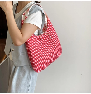 Detail of reversible gingham tote bag with red bow pattern lining and tie straps