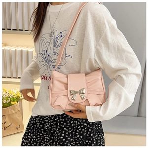 Close-up of pink shoulder bag with shiny metallic bow detail and leather texture