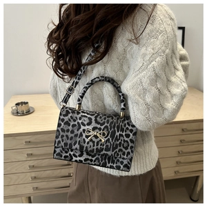 Detailed view of leopard print crossbody bag with golden bow clasp and strap on a model
