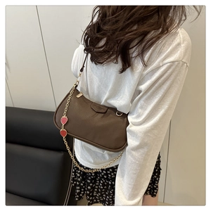 Close-up of brown litchi pattern bag with gold chain and strawberry charms decoration