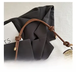 Detail of hand-woven straw tote with brown leather knotted handle and zip closure