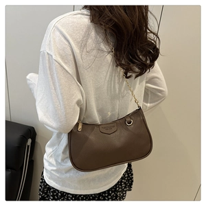 Detail of dark brown lychee pattern leather underarm bag with gold chain strap