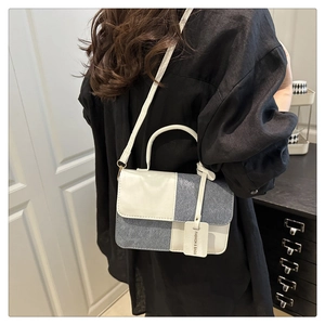 Detail of color-block crossbody bag with denim patchwork and fashion tag on black shirt