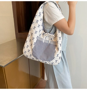 Close-up of canvas tote bag featuring navy bow prints and black checkered lace pocket