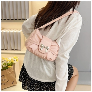 Detail of pink faux leather shoulder bag featuring a large bow and silver metallic clasp