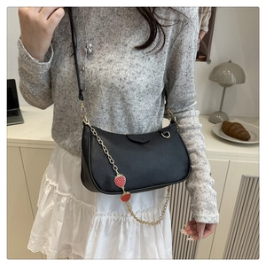 Detail of black lychee leather bag with gold chain strap and red strawberry charms