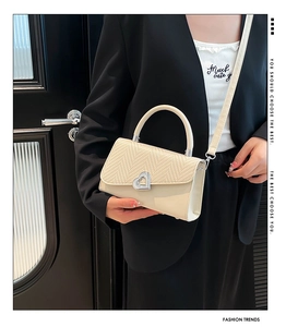 Detail of cream PU and woven texture handbag with silver heart-shaped metal buckle