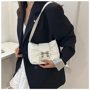 Détail d'un sac à main blanc plissé avec boucle en nœud argenté et bandoulière élégante