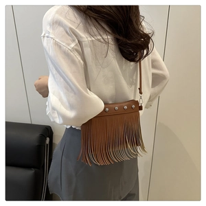 Brown tassel crossbody bag with silver studs and long fringe detail on female model