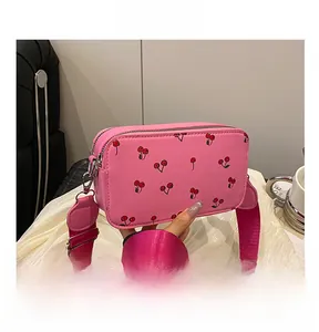 Detailed view of pink cherry print shoulder bag with adjustable wide fabric strap