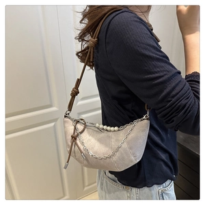 Detail of beige crescent bag with brown knotted strap, silver chain and pearl accents