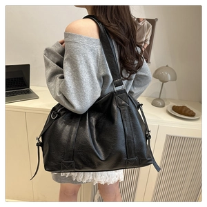 Chic black oversized tote bag featuring pebble grain texture and wide silver-buckle strap