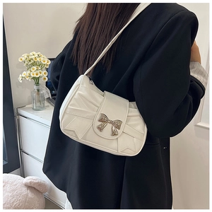 Detail of cream white pleated shoulder bag with bow buckle worn by a model