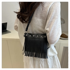 Detail of black leather crossbody bag with silver rivets and long fringe tassels on bottom