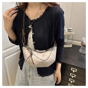Détail du sac croissant beige avec texture suédine et chaîne décorative en perles