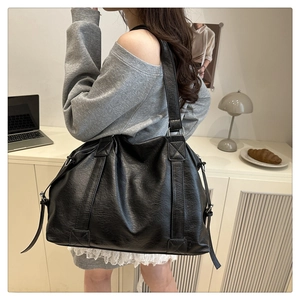 Black leather tote bag shown in a stylish home setting with laptop and desk accessories