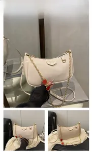 Detailed close-up of white lychee leather handbag with cute red strawberry charms and gold chain